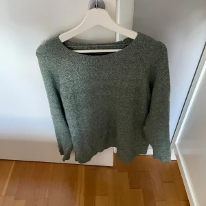 Grön stickad tröja från Vero Moda - Mysig grön stickad tröja från Vero Moda i storlek L. Tröjan har rund halsringning och långa ärmar, perfekt för kyliga dagar. Enkel och stilren design som är lätt att matcha med dina favoritjeans eller kjol.