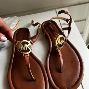 Bruna sandaler Michael Kors skinn - Snygga bruna sandaler från Michael Kors i skinn med guldfärgad MK-logga framtill. Knappt använda 