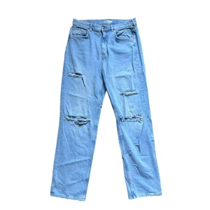 Ljusblå ripped straight jeans - Snygga ljusblå jeans med raka ben och slitna detaljer på låren och knäna. Klassisk femficksmodell i denim med normal passform och hög midja. Perfekta för en avslappnad och trendig look.