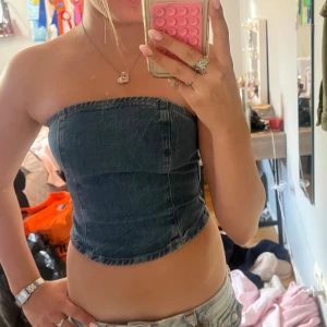 Jeans tubtopp från Never Denim XS - Säljer en snygg jeans tubtopp från Never Denim i storlek XS. Toppen är bandeau-modell, croppad och har dragkedja i ryggen. Mörkblå denim ger en cool vibe och passar perfekt till höga jeans eller kjol. Enkel och stilren design utan ärmar.