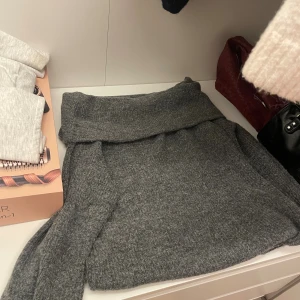 Grå stickad off shoulder från H&M - Mysig grå stickad off shoulder från H&M i storlek S. Tröjan har en bred polokrage och är långärmad, perfekt för kyliga dagar. Den är i en klassisk mörkgrå nyans och har en avslappnad passform som är både bekväm och snygg.