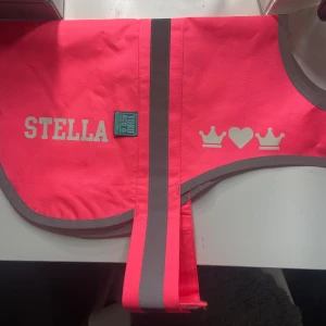 Hund reflex rosa - Helt oanvänd reflex väst till hund. Bara upp packad och provad på min hund. Den va så fin så jag beställde den även fast jag borde kunnat räkna ut att den skulle vara för stor då min hund har st 25 max. Så  är det någon hund med storlek S/30 som heter Stella så blir jag super glad. (Det är självlysande text som ni ser på bilden, storleksbeskrivning sista bilden )