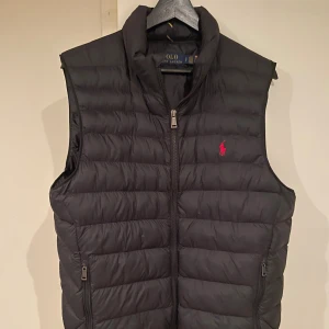 Svart dunväst från Polo Ralph Lauren - Säljer nu min svarta väst från Ralph Lauren då den börjar bli liten och jag sugen på något nytt. Storlek S men passar även M. Västen är i toppskick och inga täcken på användning. Köpt för 3000. Mitt pris 1900!!! Kom gärna med frågor och bud!