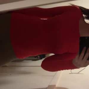 Röd långärmad topp med rund hals - Säljer en röd långärmad topp med rund halsringning. Modellen är tight och sitter snyggt mot kroppen, perfekt för dig som gillar en enkel men färgstark stil. Toppen är enfärgad och har en klassisk passform som funkar till många olika outfits.