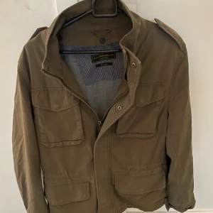 Olivgrön fieldjacket från Jack & Jones - Snygg olivgrön fieldjacket från Jack & Jones i storlek S, modellen är ca 180cm. Hör av dig vid funderingar!