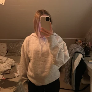 Ljusgrå stickad hoodie från Gina Tricot - Mysig stickad ljusgrå hoodie från Gina Tricot med huva och snörning. Tröjan är stickad och har en loose passform med långa ärmar. Perfekt för kyliga dagar när du vill vara både bekväm och snygg.