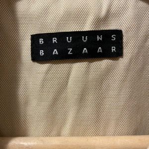 Kappa Bruuns Bazaar - Beige ofodrad kappa, Bruuns Bazaar i nyskick. Aldrig använd p.g.a. fel storlek. Storlek 36. 3 knappar fram, slits bak, 4 knappar vid arm.