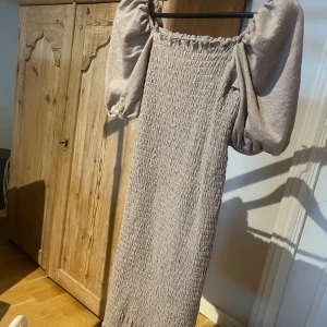 Beige långklänning med puffärmar - Supersnygg beige långklänning med smockad struktur och stora puffärmar. Storleken är ungefär S då jag sytt in den lite men inget men märker så väl