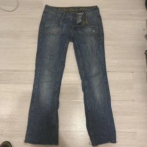 Blå bootcut jeans från Esprit - Snygga blå jeans från Esprit med bootcut passform och slitna detaljer nertill. Klassisk femficksmodell med ljusa tvättade partier och dekorativa sömmar på bakfickorna. Jeansen har låg midja och är tillverkade i mjukt denimtyg.