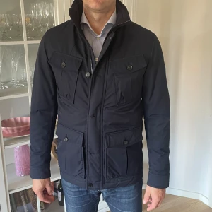 Mörkblå jacka från Oscar Jacobson - S/M - Jag säljer den här riktigt snygga jackan från Oscar Jacobson. Den är i storlek 48 vilket motsvarar S/M. Den är knappt använd och är i jättebra skick utan defekter och skador. Modellen heter Marlow Jacket. Nypris ligger på över 4000kr och jag säljer den här för 1499kr. Tveka inte att höra av er!