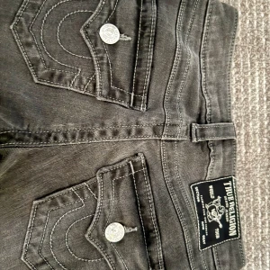 Grå/Svarta True Religion bootcut jeans - Säljer ett par svarta jeans från True Religion, modell Becca i storlek 23. Endast använda en gång ❣️priset kan diskuteras vid snabbt köp, tryck gärna på ”köp nu”❣️