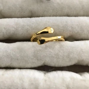 Guldfärgad ring med handdetaljer - Unik guldfärgad ring med öppet band som avslutas med två små händer. Snygg och annorlunda design som sticker ut och passar dig som gillar coola detaljer. Perfekt att bära ensam eller att kombinera med andra ringar för en personlig stil.