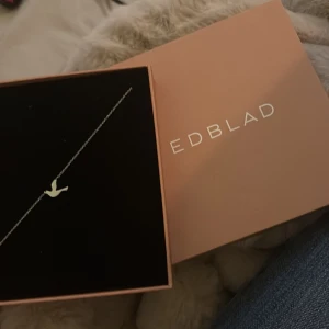 Silverfärgat halsband med fågel från Edblad - Stilrent halsband från Edblad i silverfärg med en tunn kedja och ett hänge i form av en flygande fågel. Perfekt för dig som gillar minimalistiska smycken med en liten twist. Kommer i originalask, Jag fick den i present men tyvärr hade jag redan en likadan.