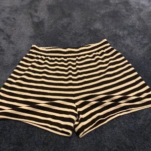 Randiga stickade shorts i svart och vitt - Snygga stickade shorts med svart och vitt randigt mönster. De har elastisk midja och två bakfickor i svart tyg. Perfekta för en chill och avslappnad stil, passar lika bra till t-shirt som hoodie.