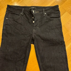 Mörkblå slim jeans från Neuw - Säljer ett par mörkblå slim jeans från Neuw, modell Iggy. Jeansen har klassisk femficksdesign, knappgylf. Snygga kontrastsömmar och stilren look som funkar till det mesta. Materialet är klassisk denim i bomull. Storlek 33/34