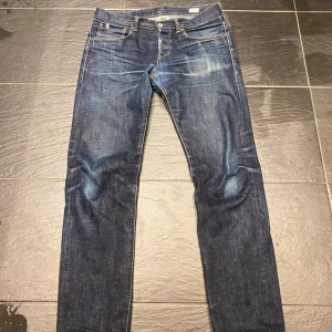 Faded denim jeans Edwin selvedge - Säljer ett par mörkblå jeans från Edwin med klassisk femficksdesign och snygga slitningar framtill. Jeansen har raka ben och kontrastsömmar i gult. Perfekt för dig som gillar en tidlös och stilren look.
