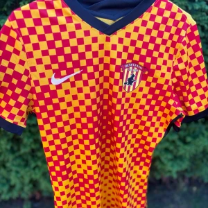 Benevento Fotbollströja - Snygg Benevento Calcio fotbollströja från Nike med röd-gult rutigt mönster på framsidan och ärmarna. Tröjan har svart V-ringad krage och svarta detaljer vid ärmslut. Tillverkad i Dri-Fit material som andas, perfekt för träning eller match. Tröjan är perfekt för dig som samlar på sällsynta fotbollströjor. Har ni några funderingar är det bara att höra av sig. Pris kan diskuteras👍