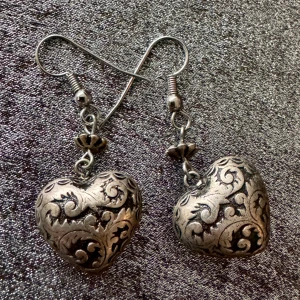 Silvriga hjärtformade örhängen - Unika örhängen i silverfärg med hjärtform och detaljerade, snirkliga mönster. De har en antik känsla och krokhänge.. Perfekta för dig som vill sticka ut med ett romantiskt och bohemiskt smycke. Väldigt lätta.