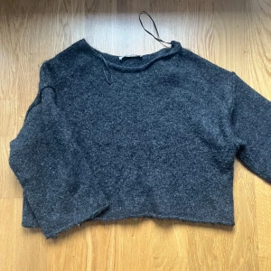 Stickad tröja  - Säljer den här stickade grå svarta tröjan med lite kortare ärmar och kortare under till.