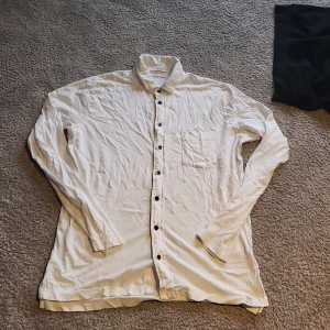 Vit skjorta från Replay i bomull - Klassisk vit skjorta från Replay i mjuk ekologisk bomull. Skjortan har långa ärmar, svart knappslå och en bröstficka. Perfekt för dig som gillar en clean och stilren look. Tröjan stryks så klart innan köp!