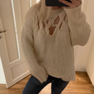 Beige stickad tröja med håldetaljer från Zara - Säljer en beige stickad tröja med coola håldetaljer upptill vid halsen. Tröjan har en relaxed fit, långa ärmar och ribbade muddar. Passar mig bra som bär S🌸