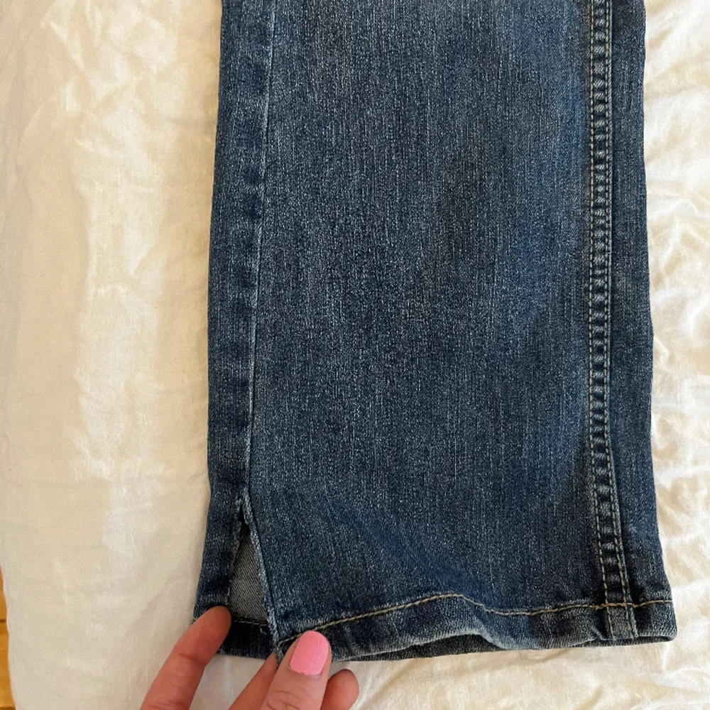Blåa jeans med super snygg baksida och knäppning! Det är uppklippta där nere. Storlek 40 Midjemått: 41cm Innerben: 77cm. Jeans & Byxor.