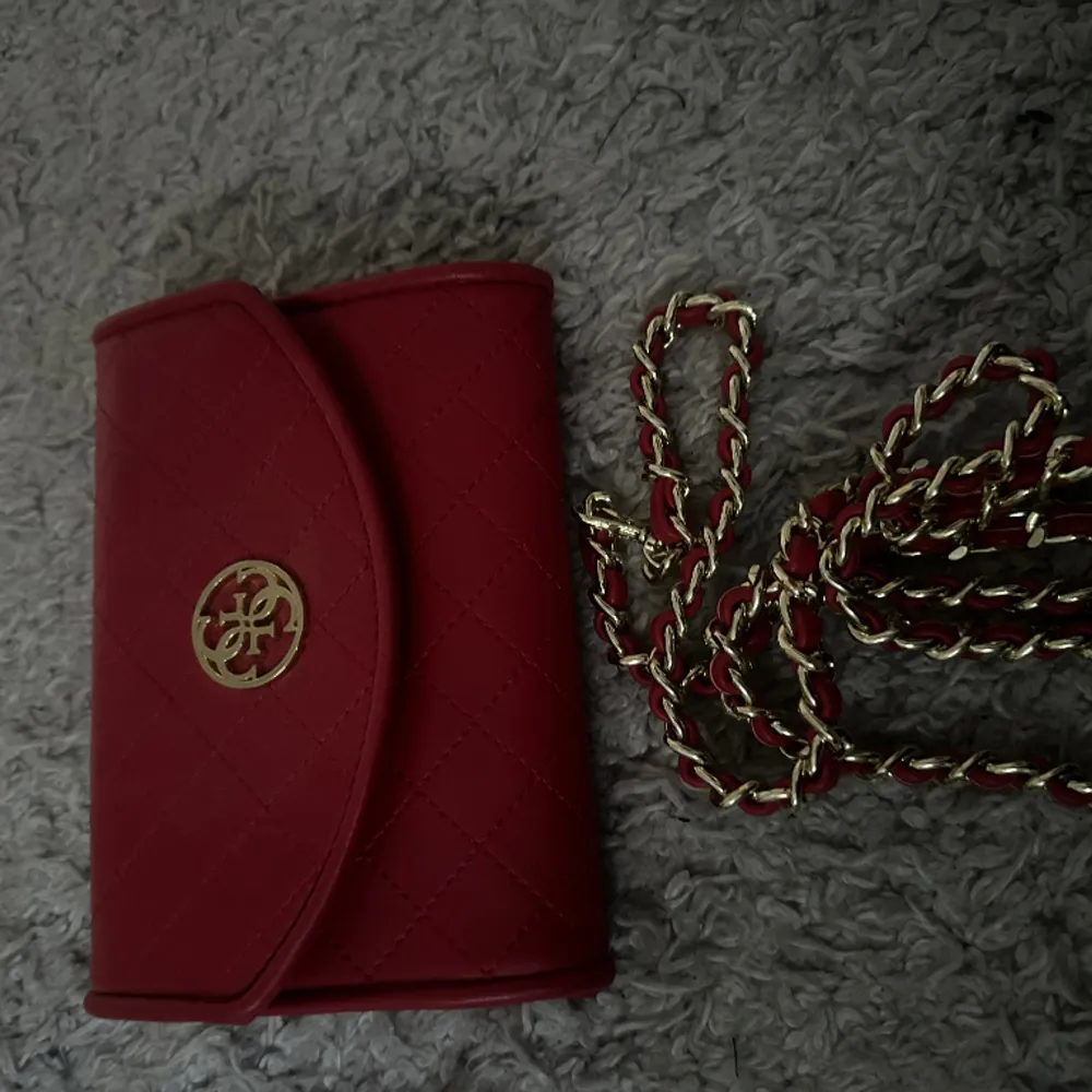 Röd plånbok från guess med band till så går att ha som väska, aldrig använt innan i fint skick . Väskor.