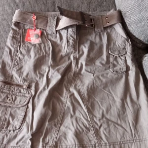 Kjol med skärp stl 40 . - Helt ny och oanvänd kjol med skärp och fickor fram samt fickor bak. Etikett sitter kvar och nypris 599.