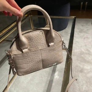 Väska - Fin beige väska från zara. Köpt för typ tre år sedan. Har ett långt band så man kan ha den över Axeln. Det silvriga på bandet är lite rosa av missfärgning men skulle inte säga att det synd när man bär den.😁