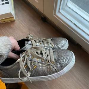 As snygga guld skor - Jag säljer skorna pg av att de tyvärr var för stora, personligen älskar jag alla smådetaljer som finns på skon, som tex. Dragkedian på sidan eller alla guldstycken. Dessa smådetaljer gör skorna unika och as snygga.