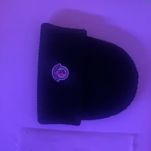 1/1 moncler mössa - En trendig moncler mössa som passar alla. Fick i present av min bror för två månader sedan och då var den helt ny. Vill köpa en äkta därför säljer jag. Skriv om du vill ha flera bilder.