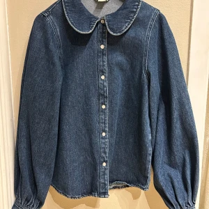Jeansskjorta med rund krage  - Jeansskjorta med ballongärm. Aldrig använd! Passar även XS.
