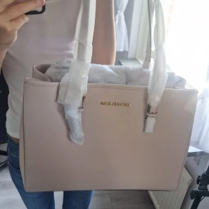 MK handväska - Super snygg Michael Kors handväska i färgen Soft Pink. Riktigt Läder. Aldrig använd och har lappen på. Skoldator får plats i den också. Skriv om ni vill ha fler bilder eller mått