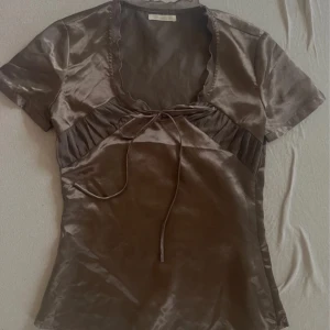 Blus - Såå fin topp/blus i en typ brun glansig färg. Älskar verkligen men den var tyvärr lite för liten i bysten för mig😞😞 köpt vintage!!
