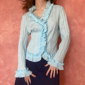 Blus med krås - Superfin, superblå eklektisk blus köpt second hand. Looove it men kommer inte t användning. Jättebra skick. Snabb affär prioriteras! Hon på bilden är 160 cm och en xs/s men den passar mig som är en M