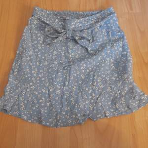 En kjol med shorts under. Kjolen är ljus blå med söta små vita blommor. Den har knyt funktion fram till och bak till så är den stretchig