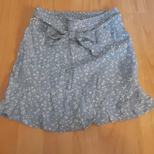 En kjol med shorts under. Kjolen är ljus blå med söta små vita blommor. Den har knyt funktion fram till och bak till så är den stretchig