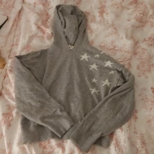 Tunn grå hoddie med stjärnor - Det är en ljus grå tunn hoddie med luva.  Den har också vits stjärnor på sig.  Den har ej använts någon gång.