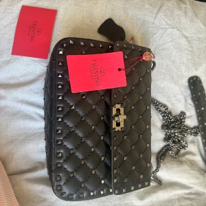 Väska - Säljer denna fina väska helt oanvänd med prislappen på. Den är svart med svart/mörk gråa nitar och kedja. Sålde en precis likadan i en annan färg (köpte dom på samma ställe) så kolla mitt konto för flera bilder☺️