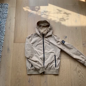 Calvin Klein regnjacka - Säljer nu min fina regnjacka från Calvin Klein i skick som ny. Fin sandbeige färg med fina detaljer. Jag på bilden är 182 cm. Hör gärna av dig vid frågor och funderingar.