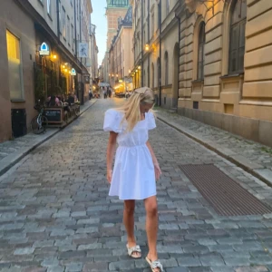 Vit kort klänning med puffärm och öppen rygg  - Säljer denna vita korta sommarklänningen. Den har puffärm med en öppen rygg med snörning samt fyrkantig halsringning. Endast använd 1 gång. Strl s och säljer för 150kr 