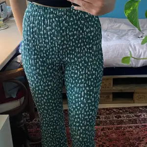 Blommiga bootcut byxor i ett ”vikt” material. Super söta, mörkgröna och vita blommor. De är långa i benen på mig som är 182 cm ! I mycket bra skick ☀️ Skriv för fler bilder eller frågor om plagget 😊