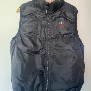 Täckväst vändbar endast provad Helly Hansen  - Helt oanvänd vändbar täckväst (svart/beige) Helly Hansen. Unisexmodell passar M/L i dam och S/M herr.   Kan mötas upp i Örebro eller skicka mot fraktkostnad 