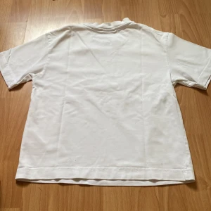 Vit t-shirt - En enkel och klassisk vit t-shirt i bomull. T-shirten har korta ärmar och en normal passform. Använd 3 gånger.