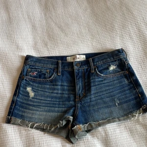 Low waist jeansshorts - As snygga lågmidjade jeans shorts från hollister som liknar hennes på bilden😊 Med jättefina detaljer på bakfickorna Säljer då de var för stora(Lånad bild)