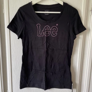 Svart Lee t-shirt - Enkel svart t-shirt med rosa tryck. Aldrig använd, endast provad. Stretchig. I mycket bra skick. Slim fit. 