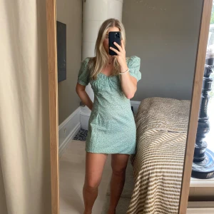 Blommig klänning  - Jag säljer denna somriga klänningen från NA-KD. Den är grön med små rosa, blå och gröna blommor. Skriv för fler bilder på klänningen🌸🪻☘️