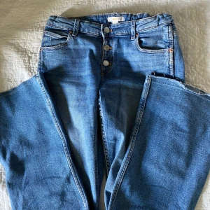Jeans - Blå jeans från Young Gina med knappar. Orginalpris 350kr, säljer för 180kr, pris går att diskuteras. Sitter bra på mig som är 162 cm. Kan vara något korta då jag klippt upp dem.