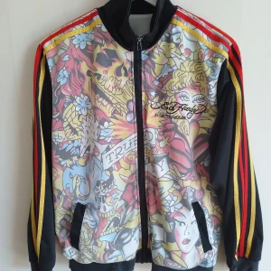 Ed Hardy track jacket stl L - Tröja i track-modell frön Ed Hardy. Storleken är L men är liten i storleken. Skicket är begagnad men bra. Har lite skav på dragkedja och en söm som gått upp vid vänster ficka (lätt fixat om man vill).
