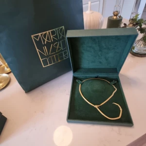 Ormhalsband från Maria Nilsdotter  - Halsband i form av orm i guldplättering. Inköpt 2018 i butiken som då låg på Sturegatan i Stockholm. Just denna kollektion säljs inte längre men finns en liknande "the Magician". Precis haft den inlämnad i butiken på rengöring, putsning och nyplätter